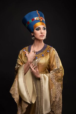 Foto de Primer plano retrato de estudio de una hermosa mujer con ojos marrones y maquillaje de noche en la imagen de la reina Cleopatra, corona, collar - Imagen libre de derechos