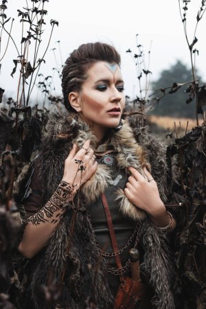 Photo for Beautiful girl warrior in armor and a fur cape with a pattern of mehendi on her arm - Royalty Free Image