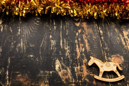 Téléchargez les photos : Plat de Noël avec place pour le texte, cheval jouet en bois et moule dorée couché sur une table en bois sombre - en image libre de droit