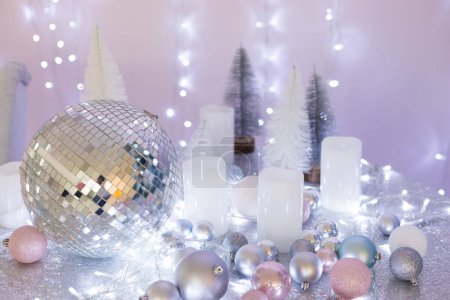 Foto de Bola disco, blanco, plata, rosa y azul bolas de Navidad y una guirnalda se encuentran en una mesa con un mantel con destellos, bokeh - Imagen libre de derechos