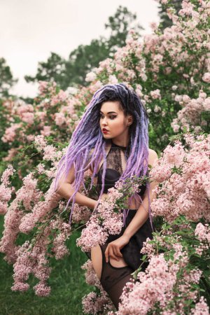 Photo for Sexy young woman model with color dreadlocks,  standing under the lilac, spring fashion portrait - Royalty Free Image