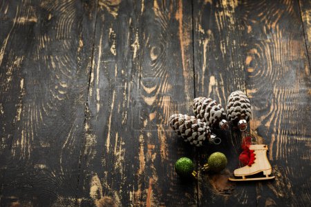Téléchargez les photos : Pose plate de Noël avec place pour le texte, boules scintillantes, patins en bois et cônes en verre reposent sur une table en bois sombre - en image libre de droit