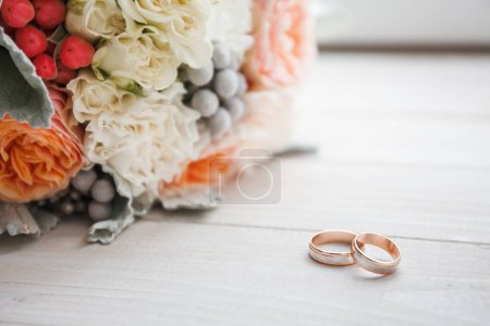 Photo for Wedding rings and a wedding bouquet lie on a white wooden windowsill - Royalty Free Image