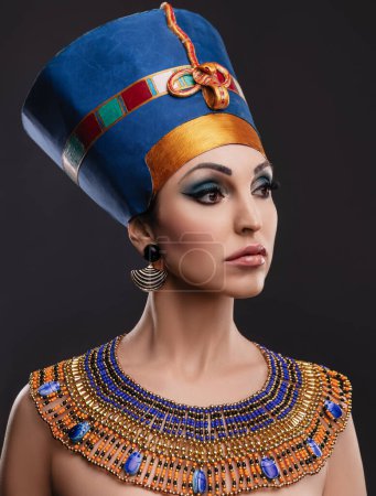 Photo for Closeup studio portrait of a beautiful woman with brown eyes and evening make-up in the image of Queen Cleopatra, crown, necklace - Royalty Free Image