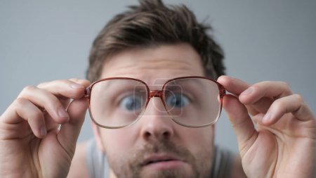 Surprised stupefied man in big glasses with WOW expression on gray backgound.