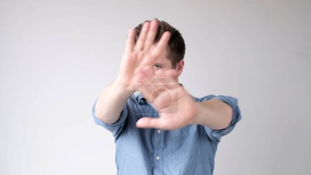 Der junge Mann aus Europa zeigt mit den Händen ein Stoppschild. Studioaufnahme