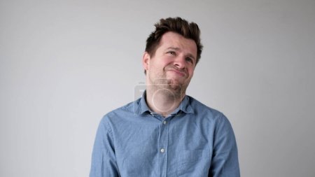 Photo for European young man is hesitating and unwilling to make decisions. He is upset about having to do unpleasant work. Studio shot - Royalty Free Image