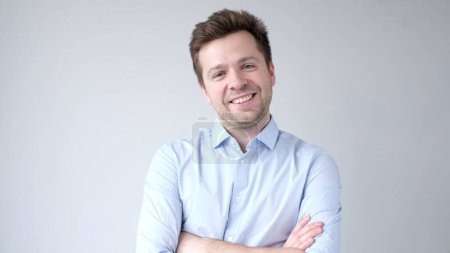 The young European man confidently looks into the camera and smiles. Studio shot