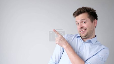 Europäischer junger Mann zeigt mit dem Zeigefinger auf eine Leerstelle für Ihre Werbung