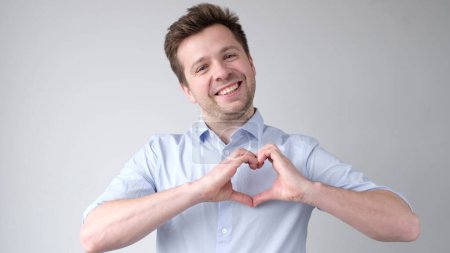 Der junge Mann aus Europa zeigt ein Herzenszeichen und gesteht die Liebe. Studioaufnahme