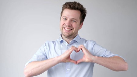 El joven europeo muestra un signo del corazón y confiesa amor. Captura de estudio