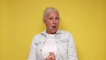 Eine ältere Europäerin ist inspiriert, schreit Wow und hebt die Hände in die Luft. Studioaufnahme