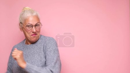 Una anciana europea con gafas mira con confianza a la cámara, sonriendo. Captura de estudio