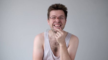 Un hombre europeo sarcástico con grandes gafas se ríe burlonamente y señala con el dedo a la cámara