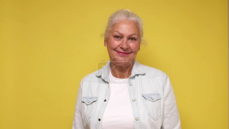 Une vieille Européenne à lunettes regarde la caméra avec confiance, souriante. Plan studio