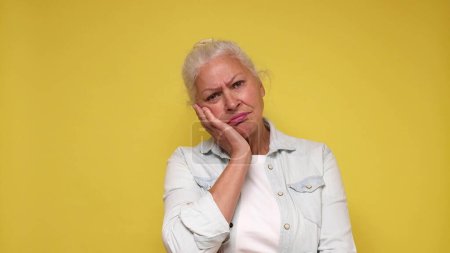 Photo for An elderly European woman with a sad expression experiences discomfort and sorrow. Studio shot - Royalty Free Image