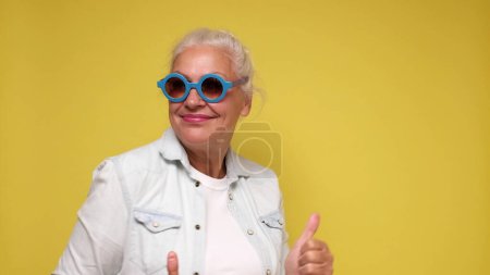 Photo for Elderly European woman in sunglasses is dancing. Studio shot - Royalty Free Image