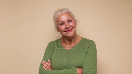 An elderly European woman confidently looks into the camera, smiling. Studio shot