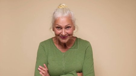 An elderly European woman confidently looks into the camera, smiling. Studio shot