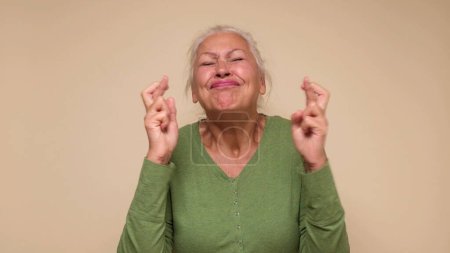 Photo for An elderly European woman crosses her fingers for good luck. Studio shot - Royalty Free Image