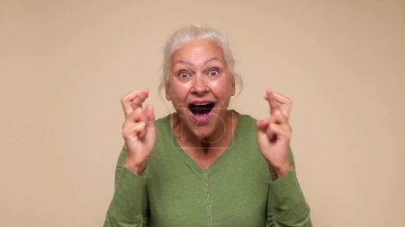 Una anciana europea cruza los dedos para tener buena suerte. Captura de estudio