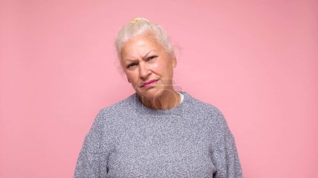 An elderly European woman with a sad expression experiences discomfort and sorrow. Studio shot