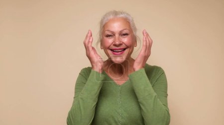 An elderly European woman is laughing. Studio shot