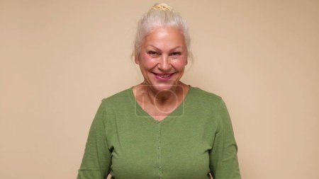 Eine ältere Europäerin mit Brille blickt selbstbewusst lächelnd in die Kamera. Studioaufnahme