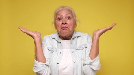Elderly European woman shrugs her shoulders in confusion