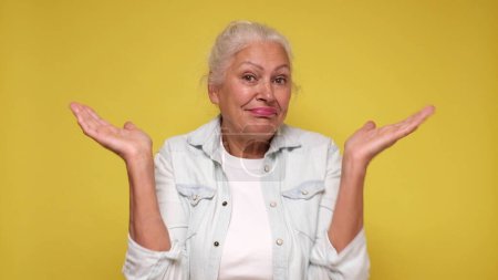 Elderly European woman shrugs her shoulders in confusion