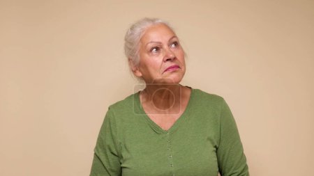 An elderly European woman looks with skepticism and distrust, not believing what she hears. Studio shot