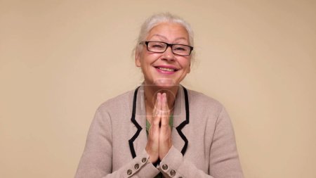 Photo for An elderly European woman is praying for help, holding her palms together. Do me a favor. Studio shot - Royalty Free Image