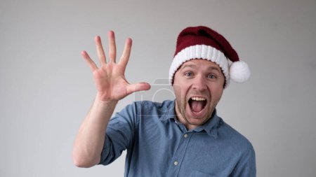 Hombre divertido en un año nuevo Sombrero cuenta los dedos, como muestra números. Captura de estudio