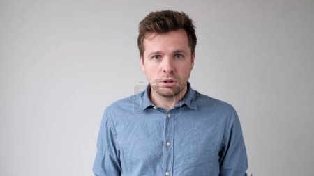 caucasian young man looks fearfully and bewilderedly into the camera