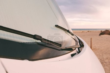 Front nose of motor home rv recreational vehicle camper van parked at the beach in free adventure travel vacation concept lifestyle. Sky and horizon in background. Road trip alternative parking