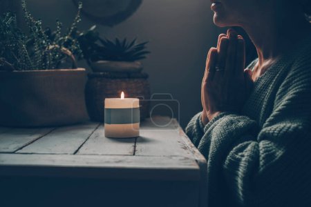 Photo for Zen like lifestyle meditation in front of a candlelight praying for one woman at home. Green mood color style. Mental health concept. Faith and religion. Candlelight in the dark indoor. Female people - Royalty Free Image