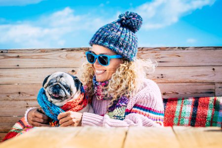 Photo for Portrait of joy woman hugging her old dog in outdoor leisure activity in winter day holiday. One female people in friendship with dog pug. People and animals together having fun and smiling outside - Royalty Free Image