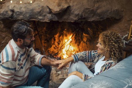 Photo for Happy young couple in romantic leisure activity at home enjoying fireplace to heating home. Romance and love with man and woman in winter holiday chalet. Romance couple love emotion concept - Royalty Free Image