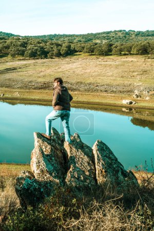 Photo for Standing man enjoy wild landscape with river and countryside woods forest. Concept of adventure and explore. Male people enjoy journey explore activity outdoor alone. Admiring lake view alone - Royalty Free Image