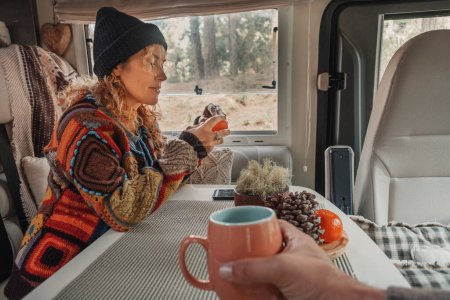 Foto de Pareja feliz disfrutar del tiempo bebiendo té dentro de una caravana. Turistas de estilo de vida nómada, personas que tienen actividad de ocio relajante dentro del vehículo autocaravana. Alquiler de transporte vacacional. Parque vista al aire libre - Imagen libre de derechos