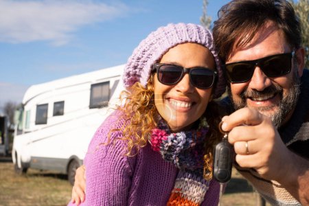 Photo for New camper van buyer people showing keys at the camera with happiness and big smile. Alternative home property buy and vacation with renting vehicle lifestyle. Mature an and woman smile together - Royalty Free Image