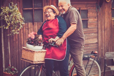 Photo for Old senior couple have fun together playing and joking outdoor on a bike. Active mature man and woman aging youthfully with love and happiness. Active lifestyle for elderly people enjoying life - Royalty Free Image