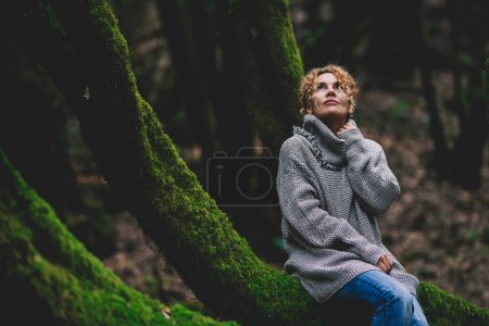 Foto de Mujer serena sentada y relajada en un tronco cubierto de almizcle verde en bosques forestales. Felices mujeres del medio ambiente disfrutando de la naturaleza y al aire libre actividad de ocio solo en el sentimiento y el amor con la naturaleza - Imagen libre de derechos