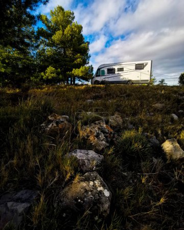 Foto de Modern camper van motor home parked in the free nature alone. Mountains countryside travel concept with vehicle. Vanlife. Alternative transport for holiday vacation. Vertical image. Road trip - Imagen libre de derechos