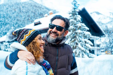 Téléchargez les photos : Happy  mature couple of tourist enjoy together winter holiday vacation time. Home chalet and mountains with trees in background. Travel man and woman concept lifestyle Love and friendship outdoor - en image libre de droit