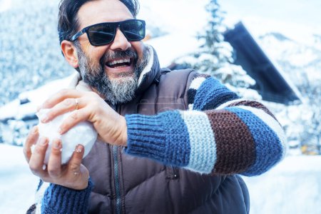 Téléchargez les photos : Happy man having fun playing with snowball, snow ball with friends or wife. Portrait of activity, winter holiday vacation leisure activity. Youthful and playful adult man attitude. Cheerful people - en image libre de droit
