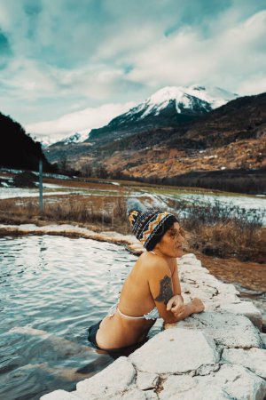 Téléchargez les photos : Tourist woman enjoy winter hot thermal water natural spa for wellness and new experience in outdoors with snow mountains view. Female people leisure activity in nature pool and  travel destination - en image libre de droit