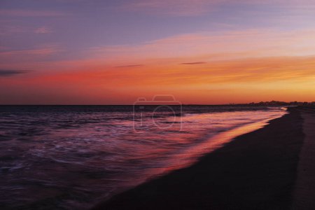 Téléchargez les photos : Long exposure amazing color sunset at the ocean beach with red sky and orange horizon. Copy space. Concept of travel destination ocean and nature beauty. Waves and sea. - en image libre de droit