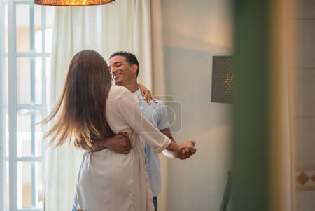 Téléchargez les photos : Romantic couple at home. An attractive young woman and handsome man are enjoying spending time together. Passionate couple is dancing on light modern room with happiness and love. Happy lifestyle people - en image libre de droit