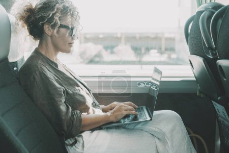 Photo for Woman working on bus with laptop during passenger travel. Businesswoman modern lifestyle people, digital nomad. Smart working with computer sitting on seat in transport vehicle, Middle age female - Royalty Free Image